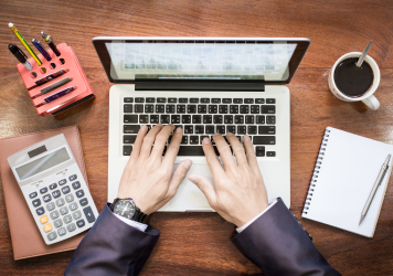 top-view-of-business-man-hands-working-on-laptop-or-tablet-pc-on-wooden-desk 1